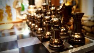 A close-up of polished bronze chess pieces on a checkerboard, highlighting the intricate details of the set.