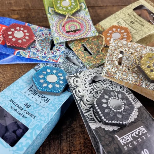 Colourful incense cone packages arranged on a wooden surface, showcasing various designs and vibrant colours.