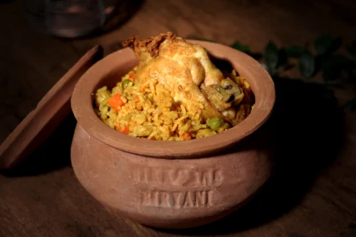 Clay pot filled with vibrant biryani, featuring rice, vegetables, and a piece of chicken, showcasing food photography expertise.