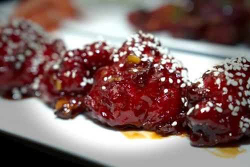Glazed red food garnish topped with sesame seeds, showcasing vibrant food photography for commercial use.