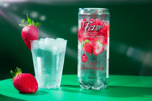 Sparkling strawberry water in a can beside a glass filled with ice and strawberries, showcasing vibrant food photography.
