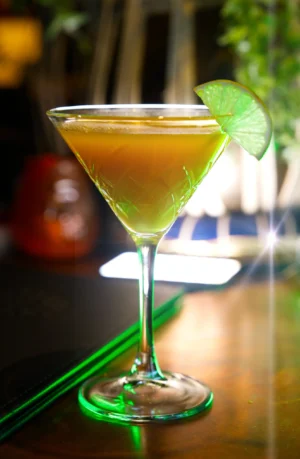 A vibrant cocktail served in a stylish glass, garnished with a lime slice, showcasing expert food photography.