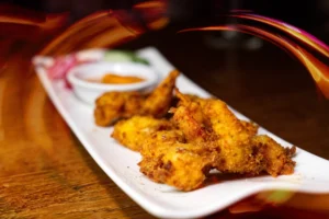 Crispy golden fried food served on a white plate with dipping sauce, showcasing specialised food photography.